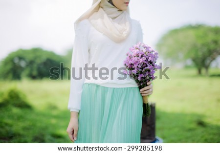 Closeup image of half length body portrait woman hold purple wedding flower bouquet decoration on left hand with outdoor background, wedding concept