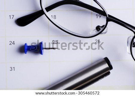 Blue push pin pointed to 25th day of the month with a pen and spectacles, national voter\'s day, world malaria day, christmas day concept