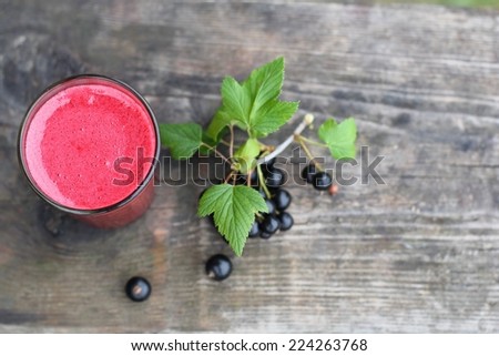 Black currant juice on a wooden board with clack currant leaves and berries.