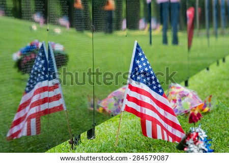 American Flag sits next to a traveling Vietnam memorial wall with the flags reflection.