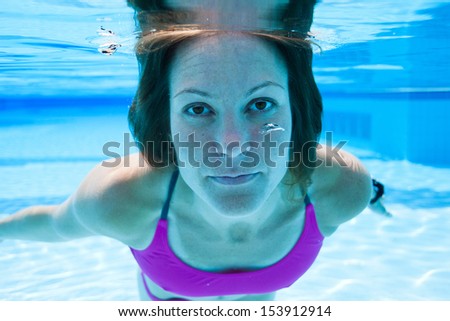 Closeup of female swimmer underwater in swimming pool with eyes open