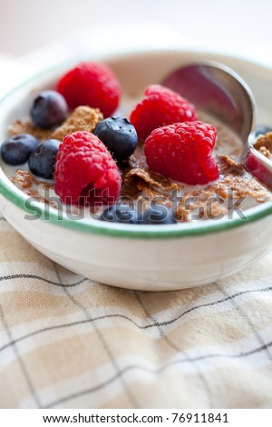 Bowl of cereal with raspberries, blueberries and milk for healthy breakfast.
