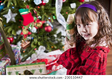 well hold on, what\'s this? / little girl checking a gift / to see what\'s inside