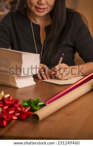 woman writing cards / looks like they are for christmas / judging by decor