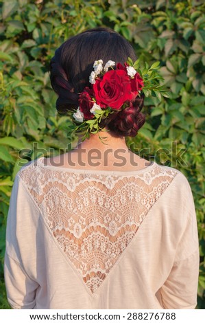 girl\'s hairstyle with fresh flowers on the green leafs background
