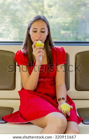 Girl eating an apple in subway car .