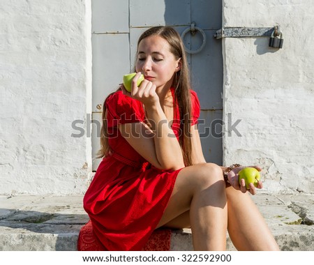 Girl sits in old park and eating apple .