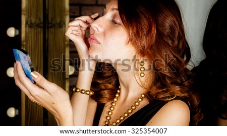 Girl looks in mirror and preens in dressing room .