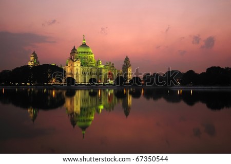 Majestic Victoria Memorial building reflected across lake at sunset