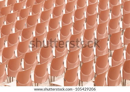 Abstract of rows of plastic chairs without people on them. Preparation for presentation or performance.