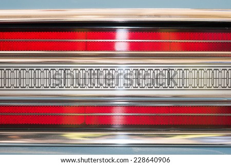 Car taillight. Blue white red black-brown symmetrical pattern with brown lines. Glare noticeable. Old or retro car light details.