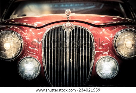 Moscow, Russia - March 3, 2013: Front headlights and grille of a restored red vintage Jaguar motor car showing the badge and hood ornament, close up frontal.