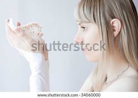 young blonde sexy girl posing with white gloves on her hands and seashell in her hands