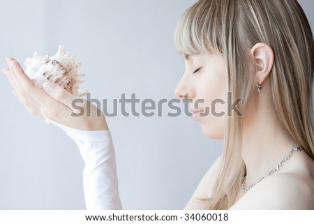young blonde sexy girl posing with white gloves on her hands her eyes closed and seashell in her hands