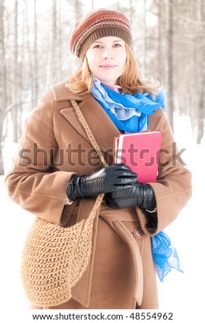 winter street portrait of young beautiful natural looking woman in casual clothes holding books and smiling