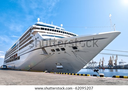 beautiful white giant cruise ship on stay at harbor, blue cloudy sky in background and visible lens flare