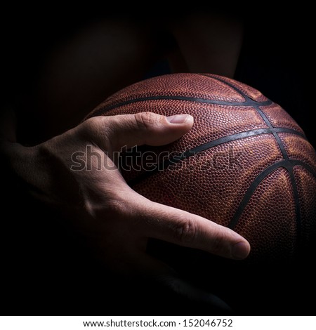 Fragment of a basketball ball in a hand of the basketball player