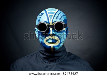 The painted man\'s face on a black background. Dark goggles