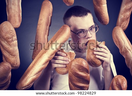 The young man wearing spectacles eats a long loaf