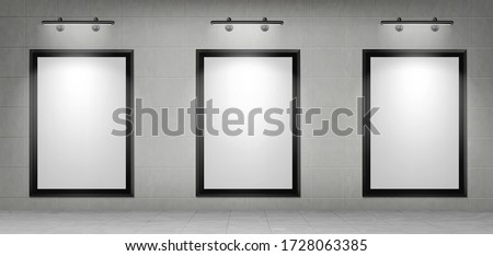 Blank movie posters illuminated by spotlights. Vector realistic mockup of white picture in black frames on gray tiled wall in cinema, theater hallway or gallery. Empty advertising banners with lamps