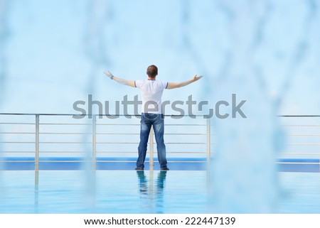 Male. Man tourist traveler raised his hands up. The joy of freedom, the fresh sea air. Everything is fine. Man against the blue sky through the flow of water. The stream of life. Striving upwards.