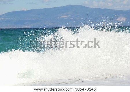 Beautiful sea, blue sky, white waves strong, sandy beach. Element of water and air. Image for background or screen saver. Concept for advertising of tourist services and leisure at the seaside.