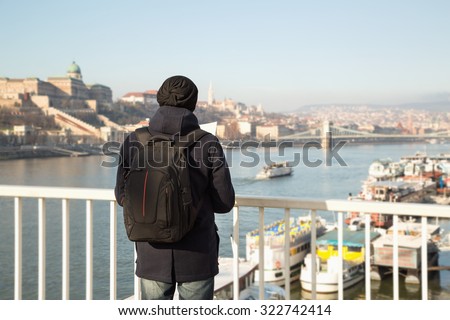 Man tourist. Young man with map in hand. He is looking from the bridge to the other side of Budapest. Winter holidays in Budapest, Hungary. Map, city, tour, travel, vacation, holiday - concept.