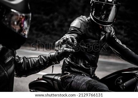 fist bump greeting of two motorbike riders in leather clothes and helmets  Imagine de stoc © 