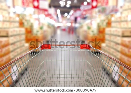 View from shopping cart trolley basket at supermarket self-service grocery shop. Retail. Blurred background.