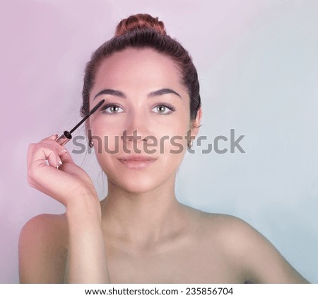 beauty portrait of a cute young girl with clean tanned skin with a mascara brush in his hand close to the eyes