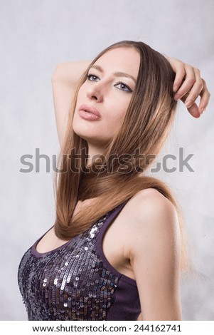 portrait of a young girl with very long blond hair on the neck in a brilliant sparkling dress
