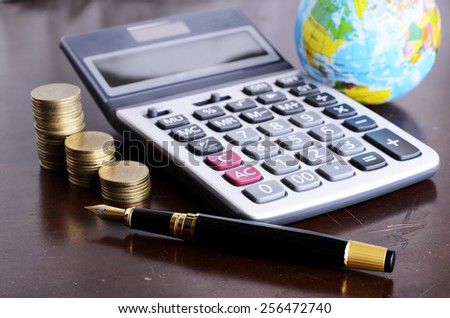 Fountain pen and calculator money coins stack and earth for Business concept