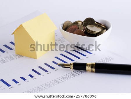 Fountain pen and house paper and coins in cup heart shaped for Home loans concept