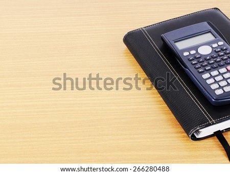 Calculator and Business book on wooden desk background