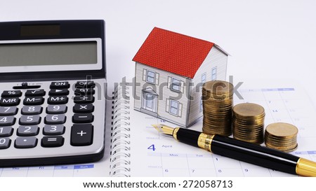 Mortgage loans concept with Fountain pen and money coins stack and paper house and calculator on calendar book pages