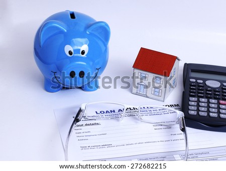 Piggy bank and paper house and calculator and eyeglasses on Loan application form