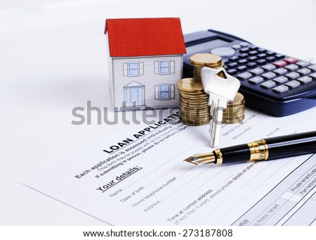 Mortgage loans concept with Fountain pen and key and calculator and paper house and coins stack on Loan Application form
