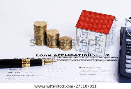 Close up of fountain pen and loan application form and coins stack and paper house and eyeglasses and calculator