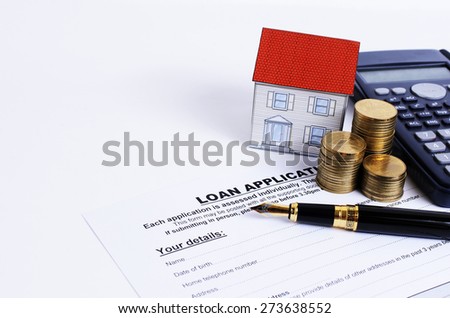 Loan application form and fountain pen and calculator and coins stack and paper house