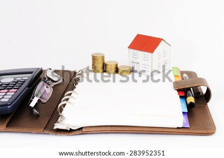Mortgage loans concept with coins stack and paper house and Eyeglasses and calculator on business memo book