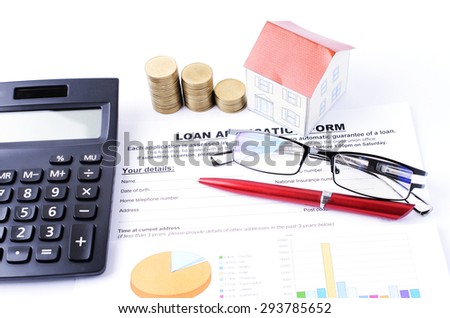 Mortgage loans concept with loan application form and coins stack and house paper and red pen and eyeglasses with calculator