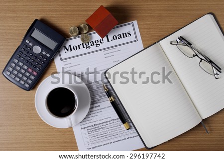 Mortgage loans concept with house paper and coins stack and coffee cup and fountain pen and calculator and eyeglasses