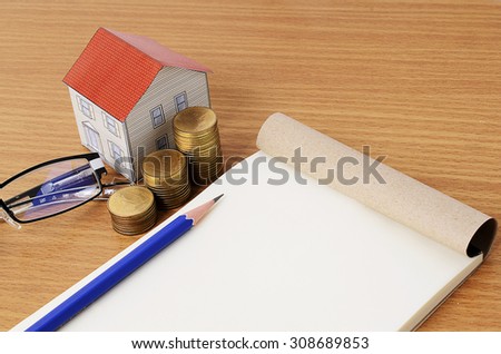 Mortgage loans concept with pencil and notepad with paper house and coins stack