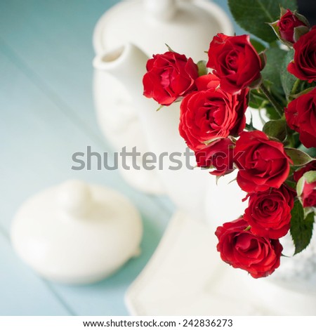 tea kettle and a bouquet of red roses
