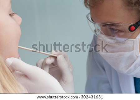 Doctor examining child\'s throat and mouth