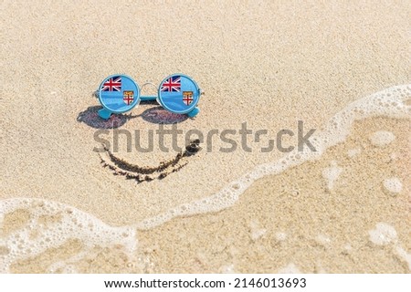 A painted smile on the sand and sunglasses with the flag of Fiji. The concept of a positive and successful holiday in the resort of Fiji. Zdjęcia stock © 