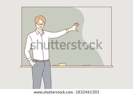 Education, training, explanation, lecture concept. Young hapy smiling man guy student teacher lecturer character explaining material on school lesson near blackboard. Educational process at university