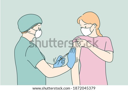 Woman doctor in protective medical mask and uniform holding syringe before making injection to young female patient in medical clinic. Vaccination, Covid-19 coronavirus vaccine concept 
