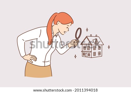 Searching for new house and real estate concept. Young positive business woman standing using magnifying glass zooming to see house or residential building details for making deal 
