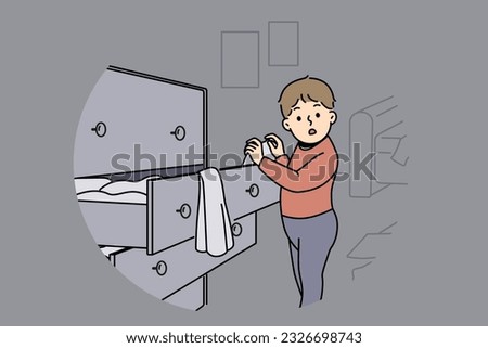 Little boy is standing near closet with clothes, looking at textiles with curiosity and studying world around. Childish pranks of funny boy throwing clothes from drawer making mess while playing